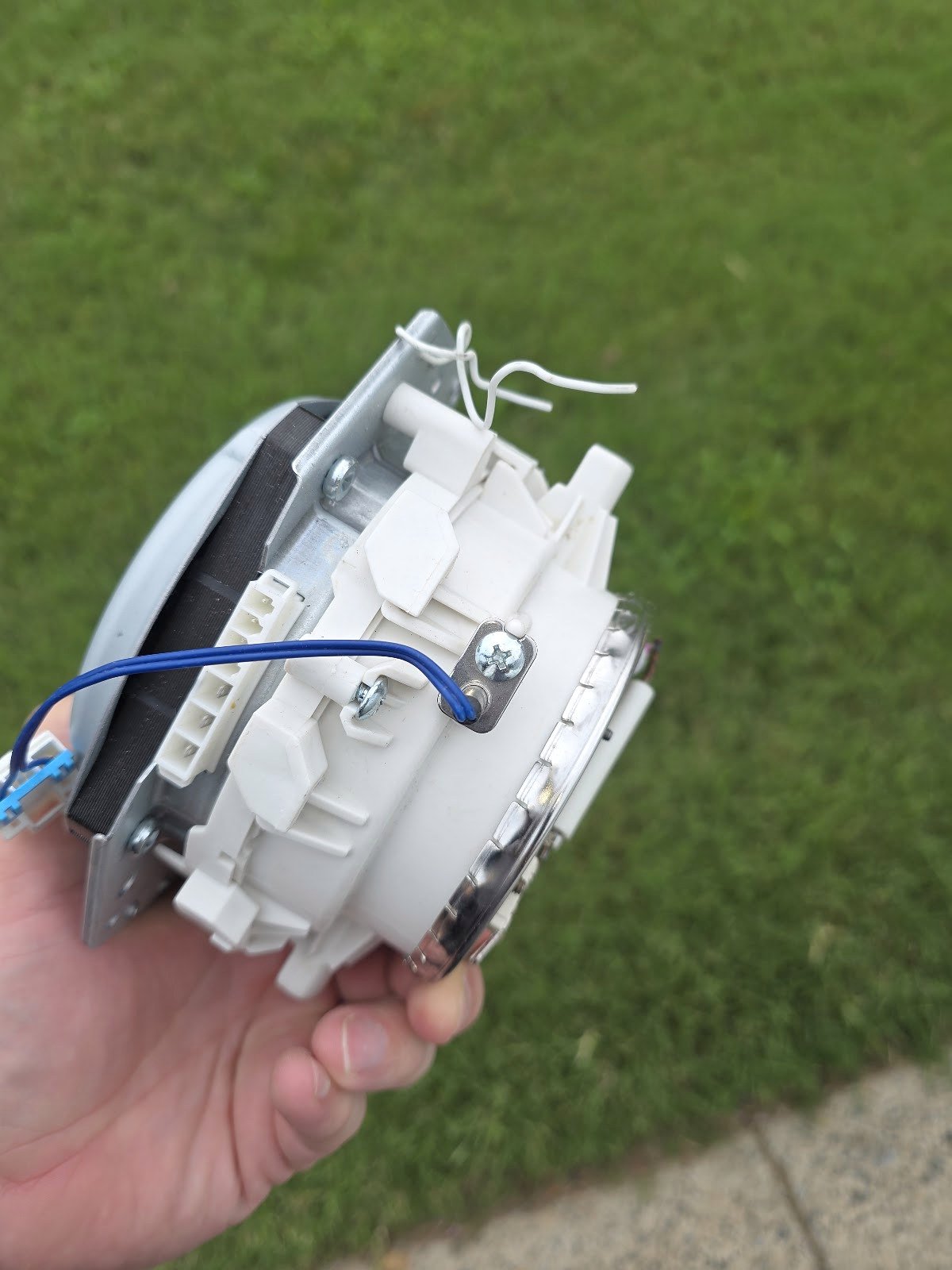 Removed dishwasher pump assembly held for inspection