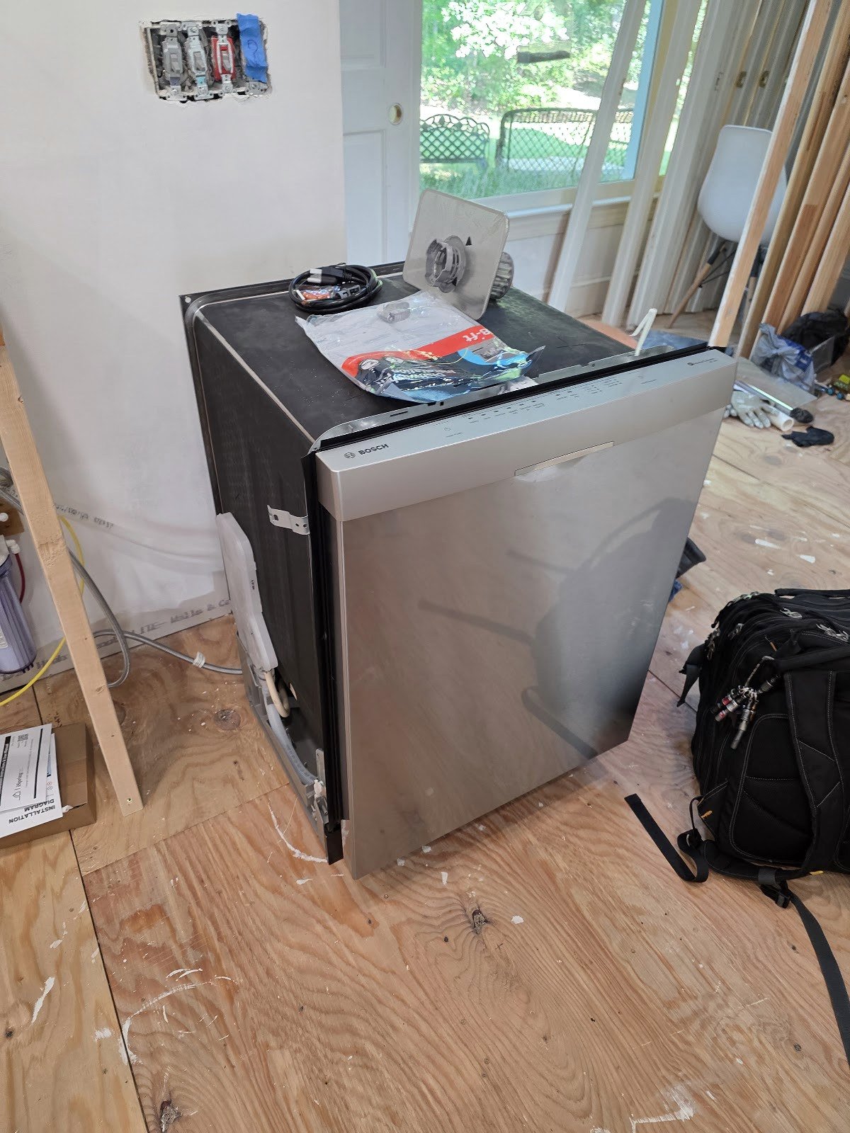Dishwasher pulled out from cabinetry with service tools nearby