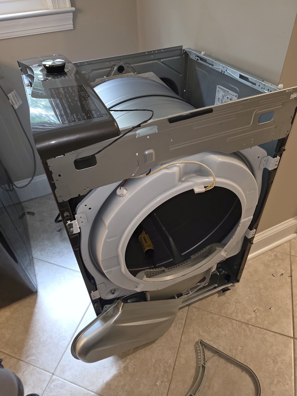 Front-load dryer with its front panel removed for access to the drum