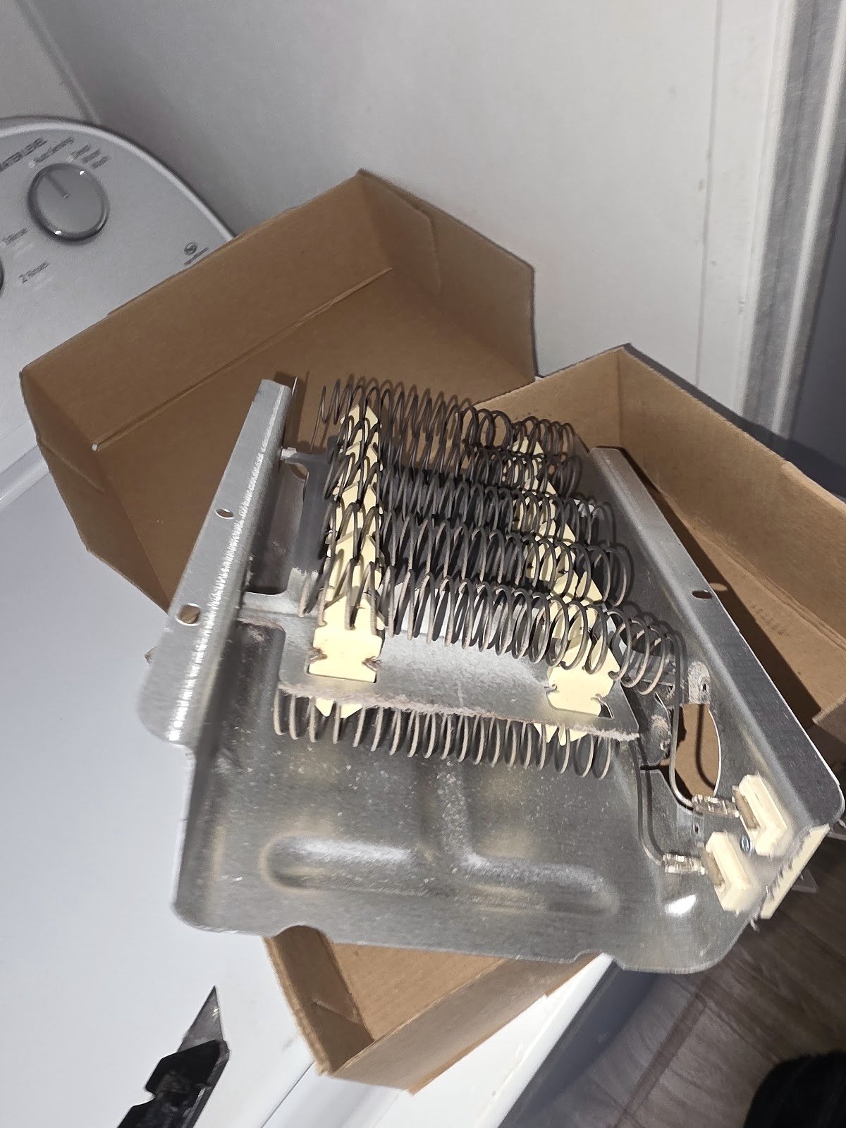 Dryer heating-element assembly resting in a parts box