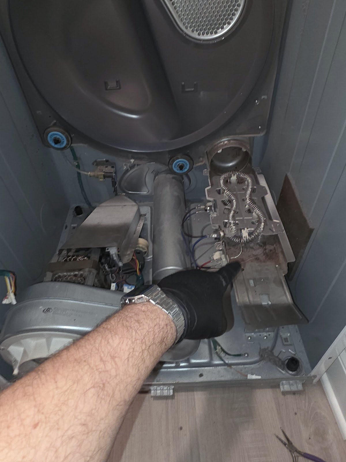 Technician inspecting a dryer heating assembly with the front panel removed