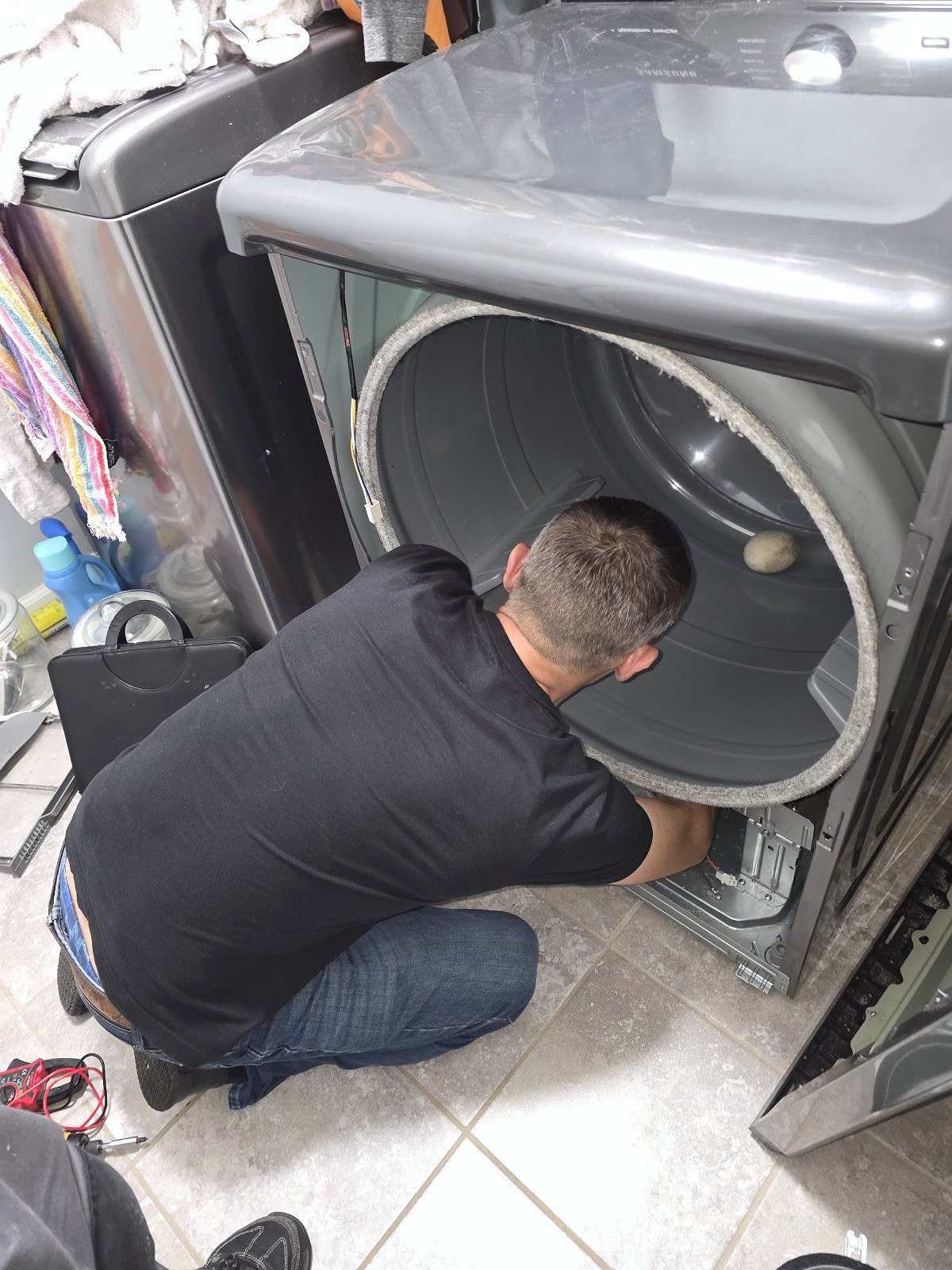 Technician working at the open front of a clothes dryer