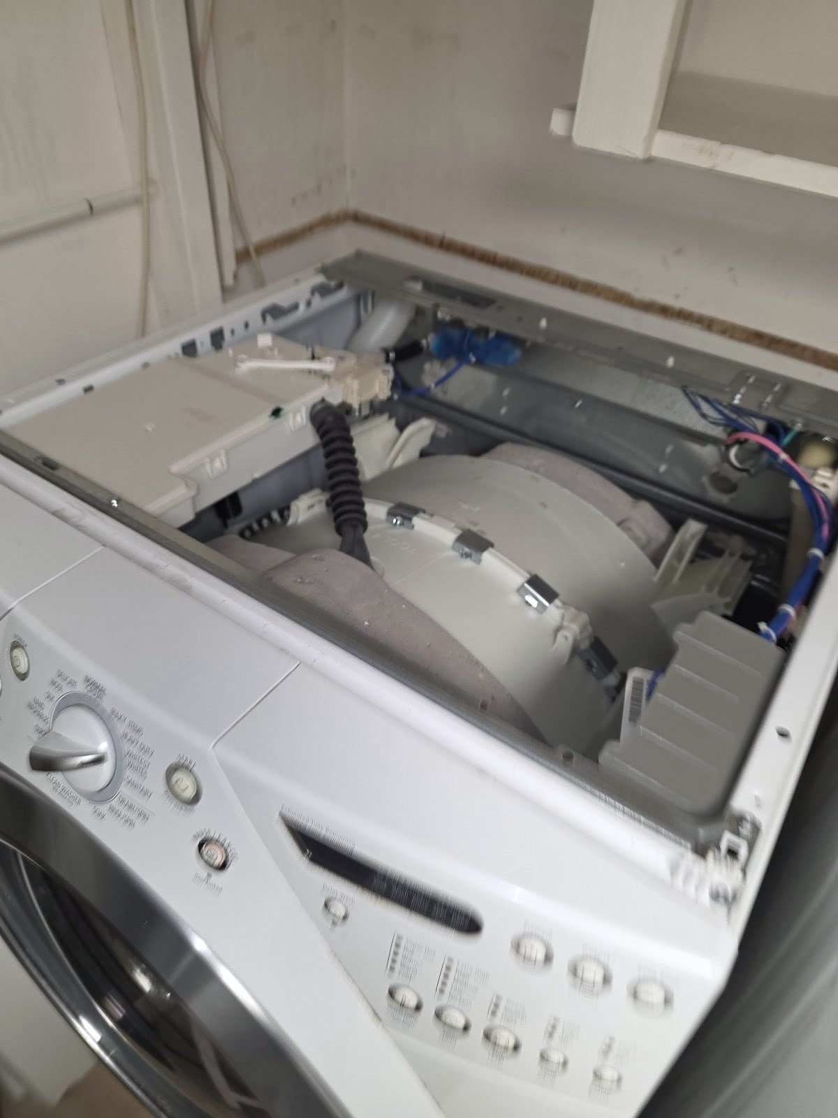 Front-load washer with its top panel removed to expose the tub and water connections