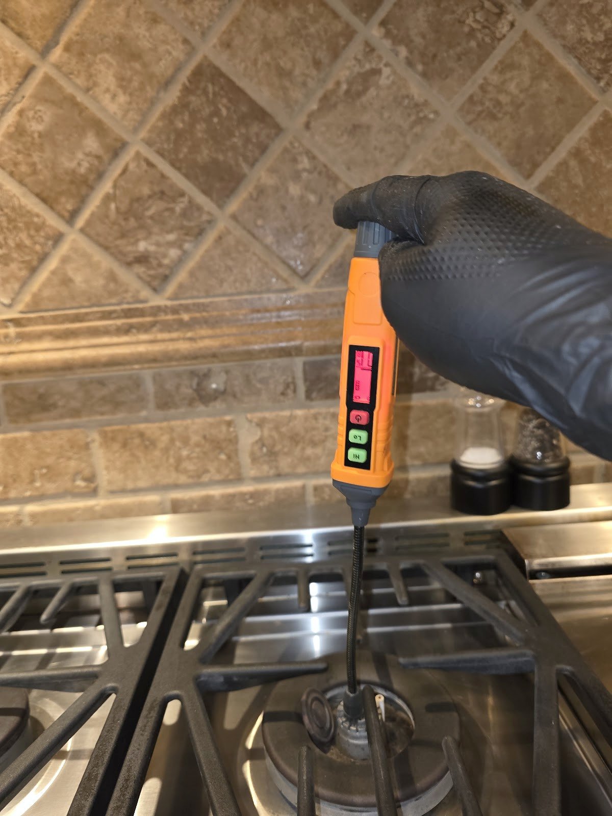 Technician holding a handheld gas detector above a range