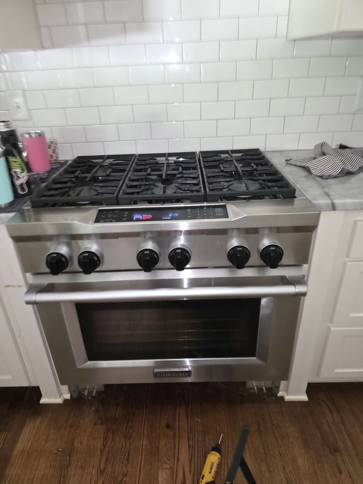 Stainless steel gas range beneath a tile backsplash