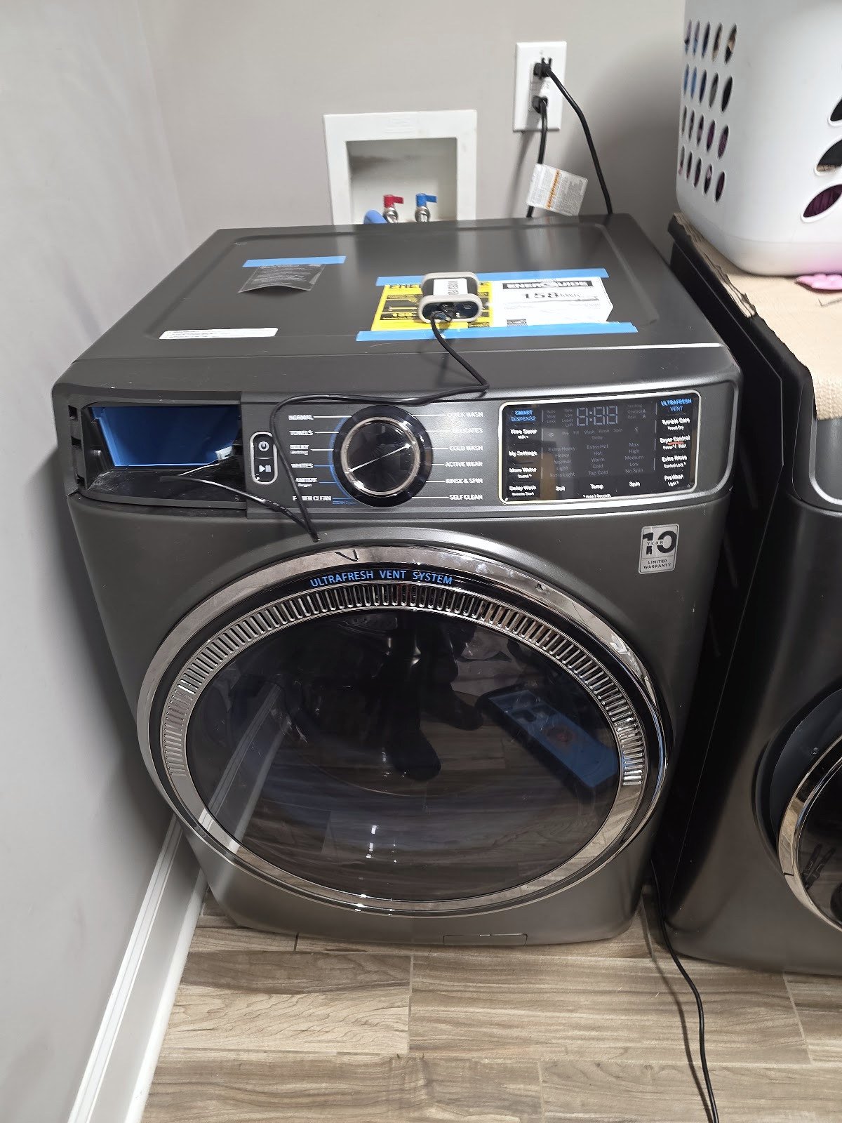 Dark front-load washing machine with a round glass door and digital controls