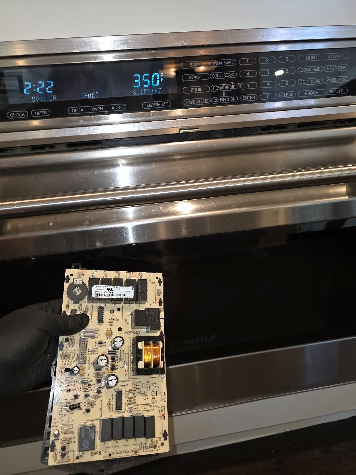 Removed electronic control board held in front of a built-in oven