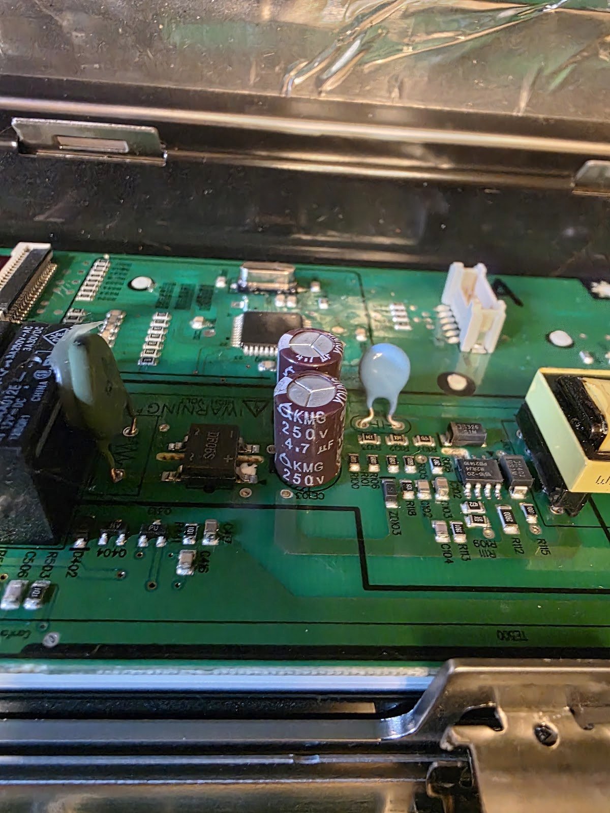 Exposed electronic circuit board and wiring behind an oven control panel