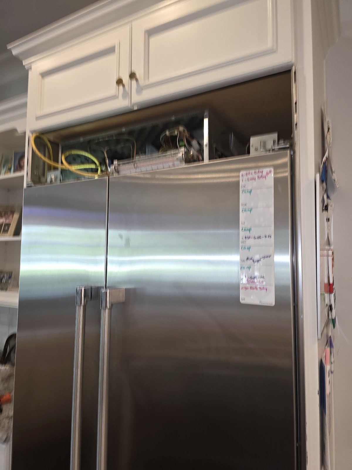 Built-in stainless steel refrigerator with the upper service grille open