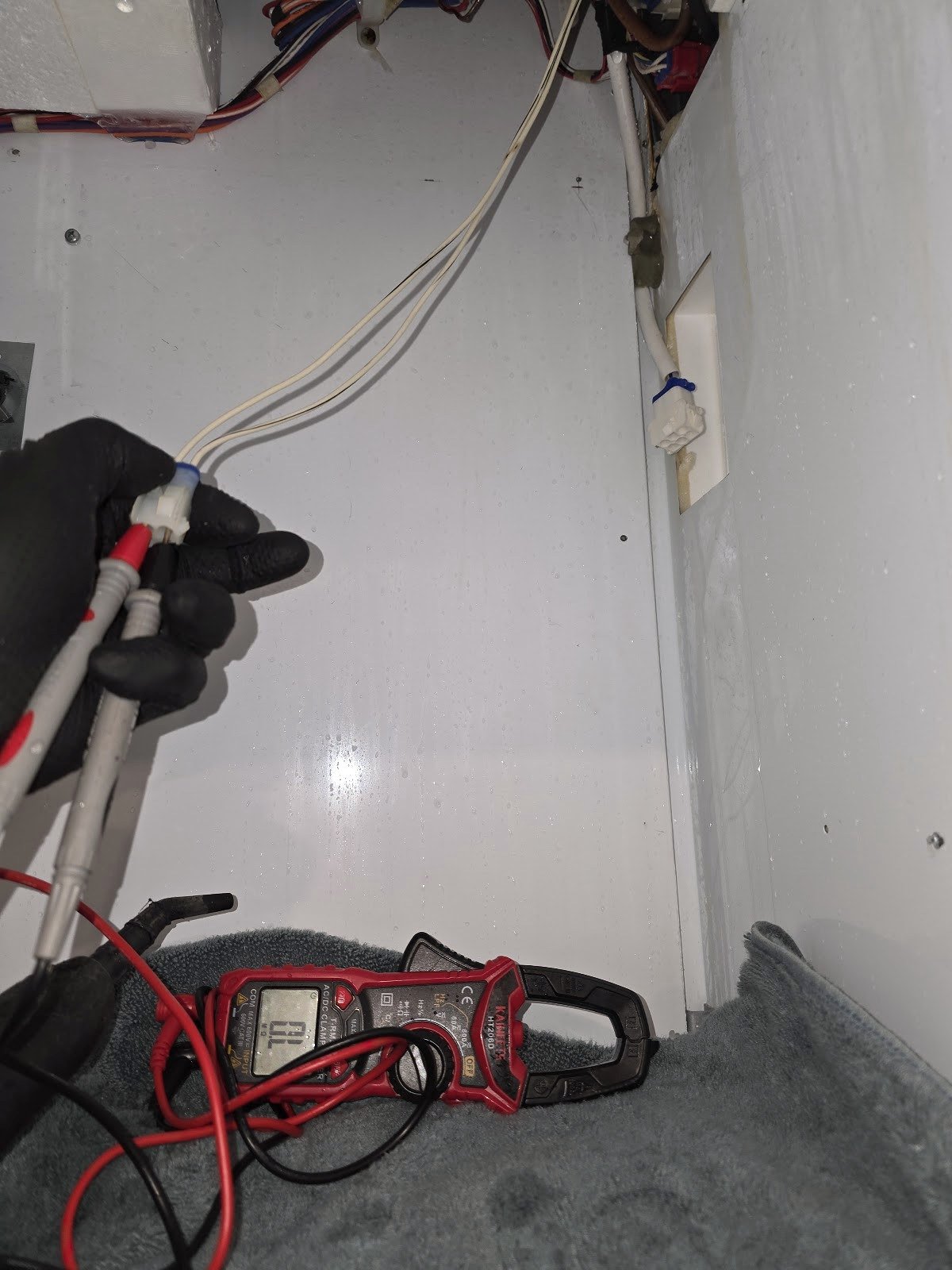 Technician using test leads inside a refrigerator compartment