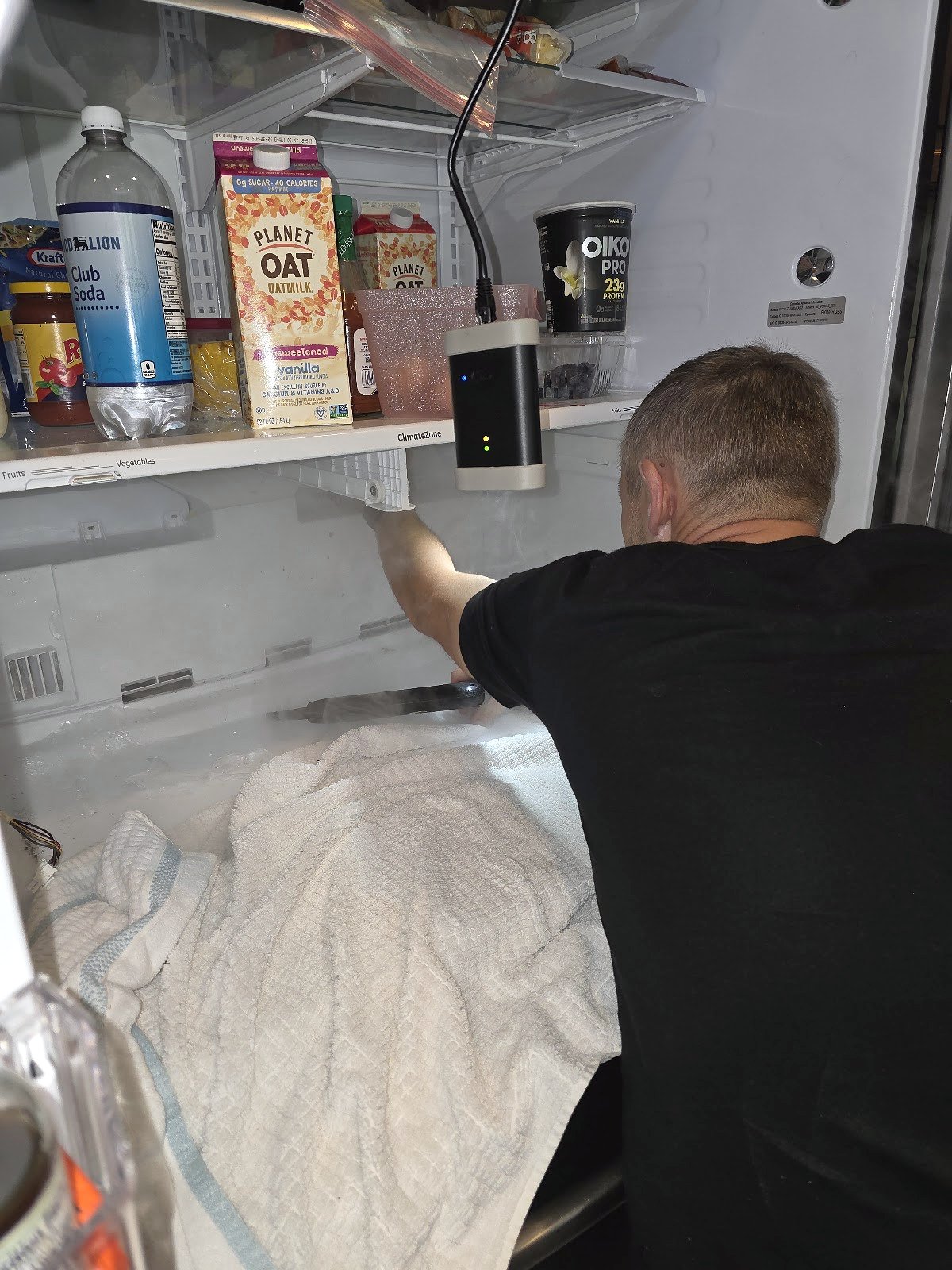 Technician working inside an open refrigerator compartment