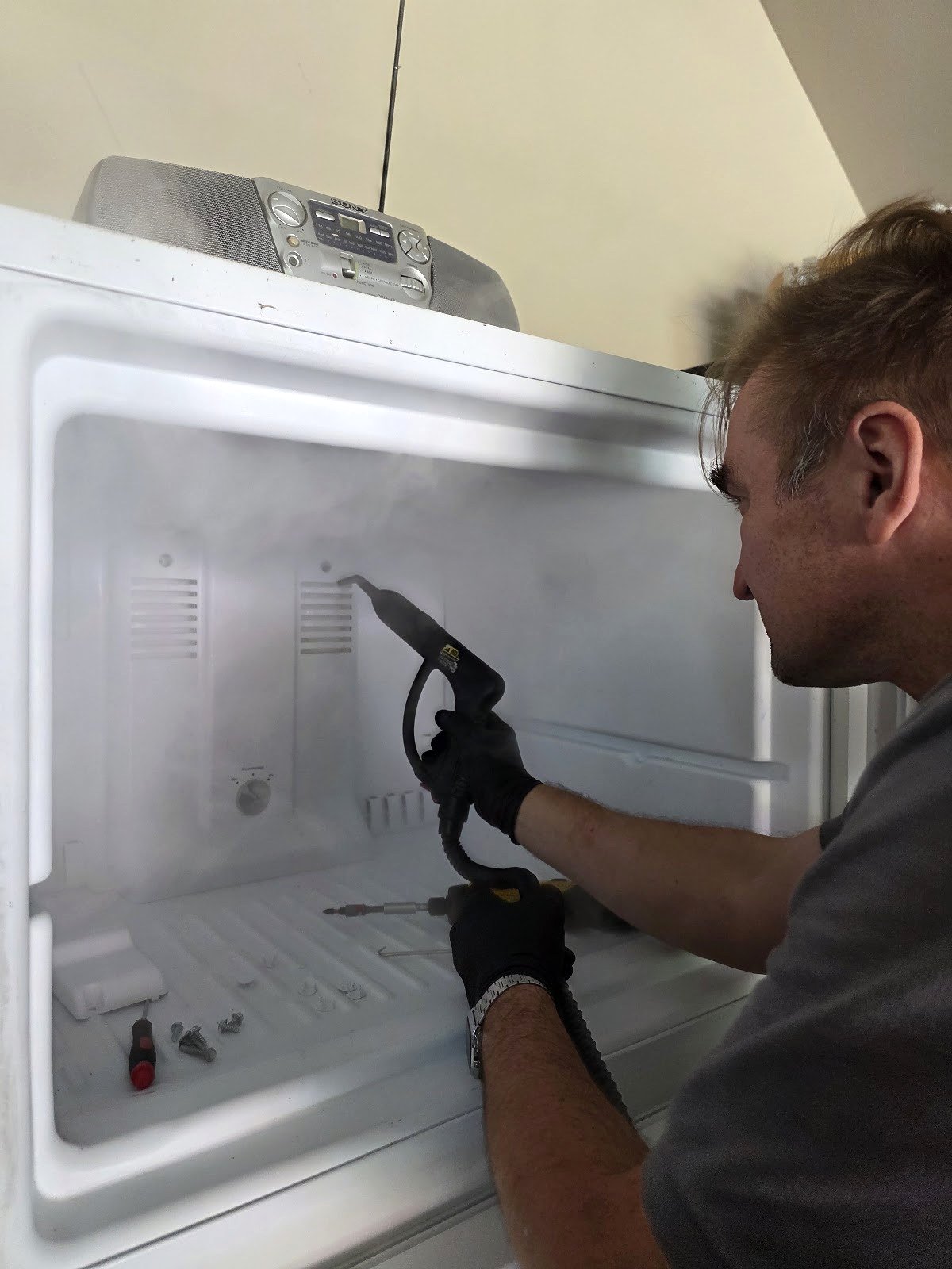 Technician inspecting the inside of a refrigerator with a handheld tool