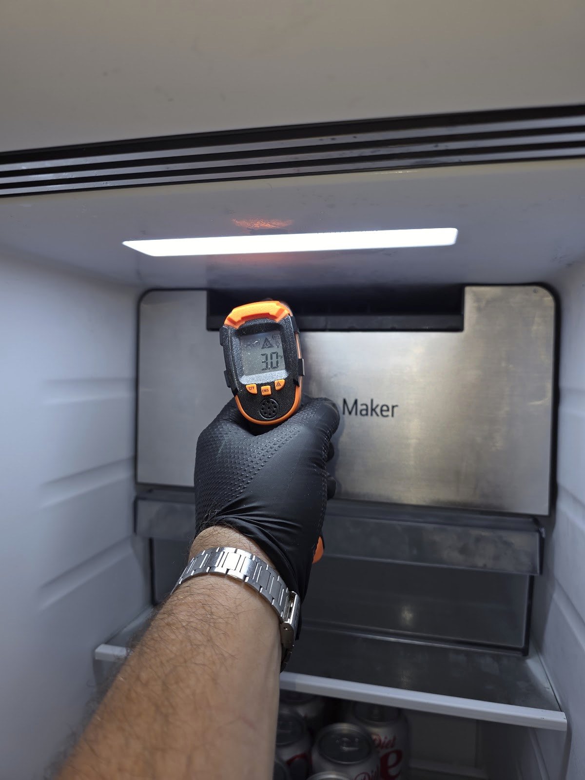 Handheld thermometer used near a refrigerator ice-maker compartment