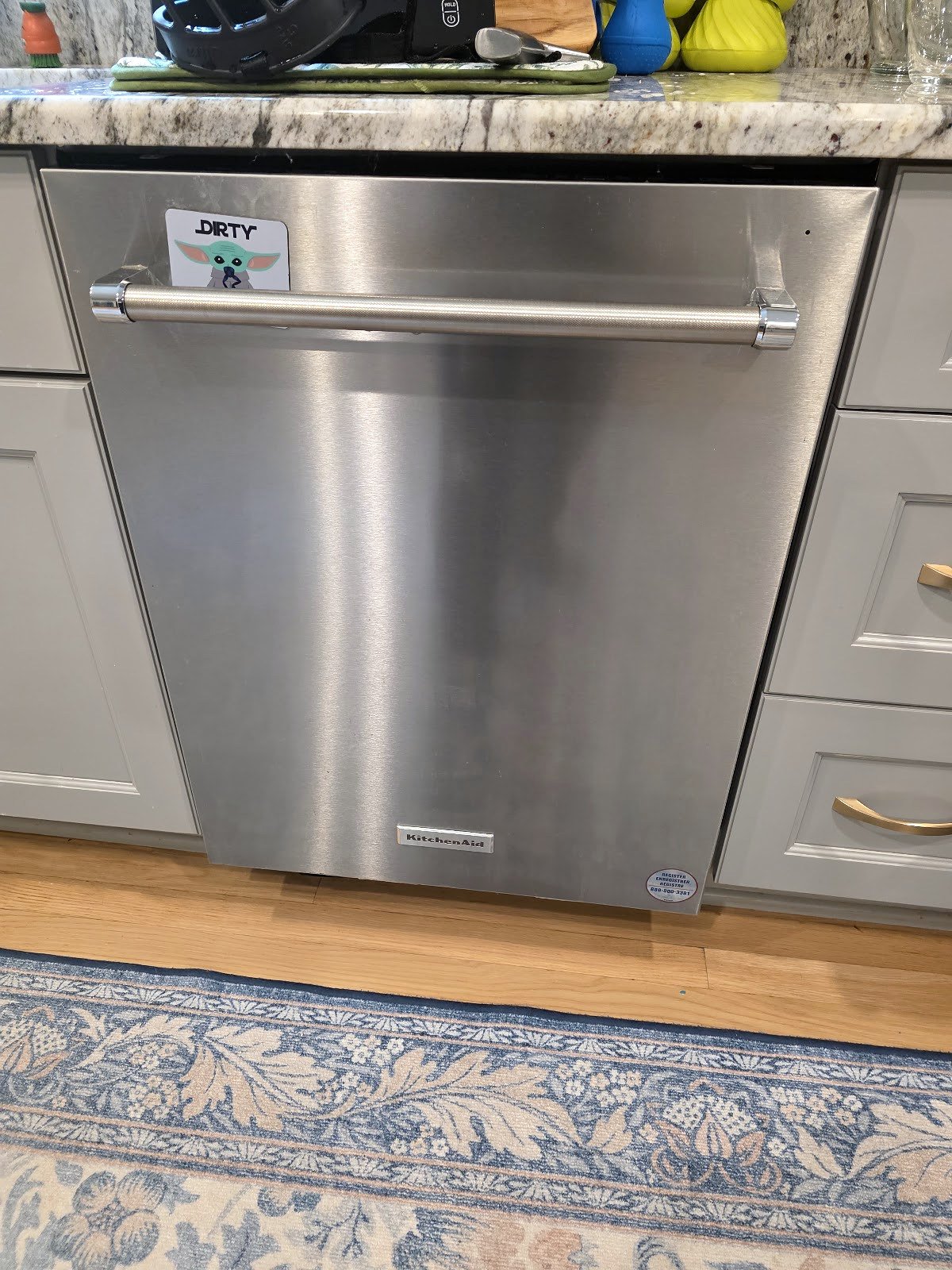 Stainless steel Samsung dishwasher beneath a stone kitchen countertop