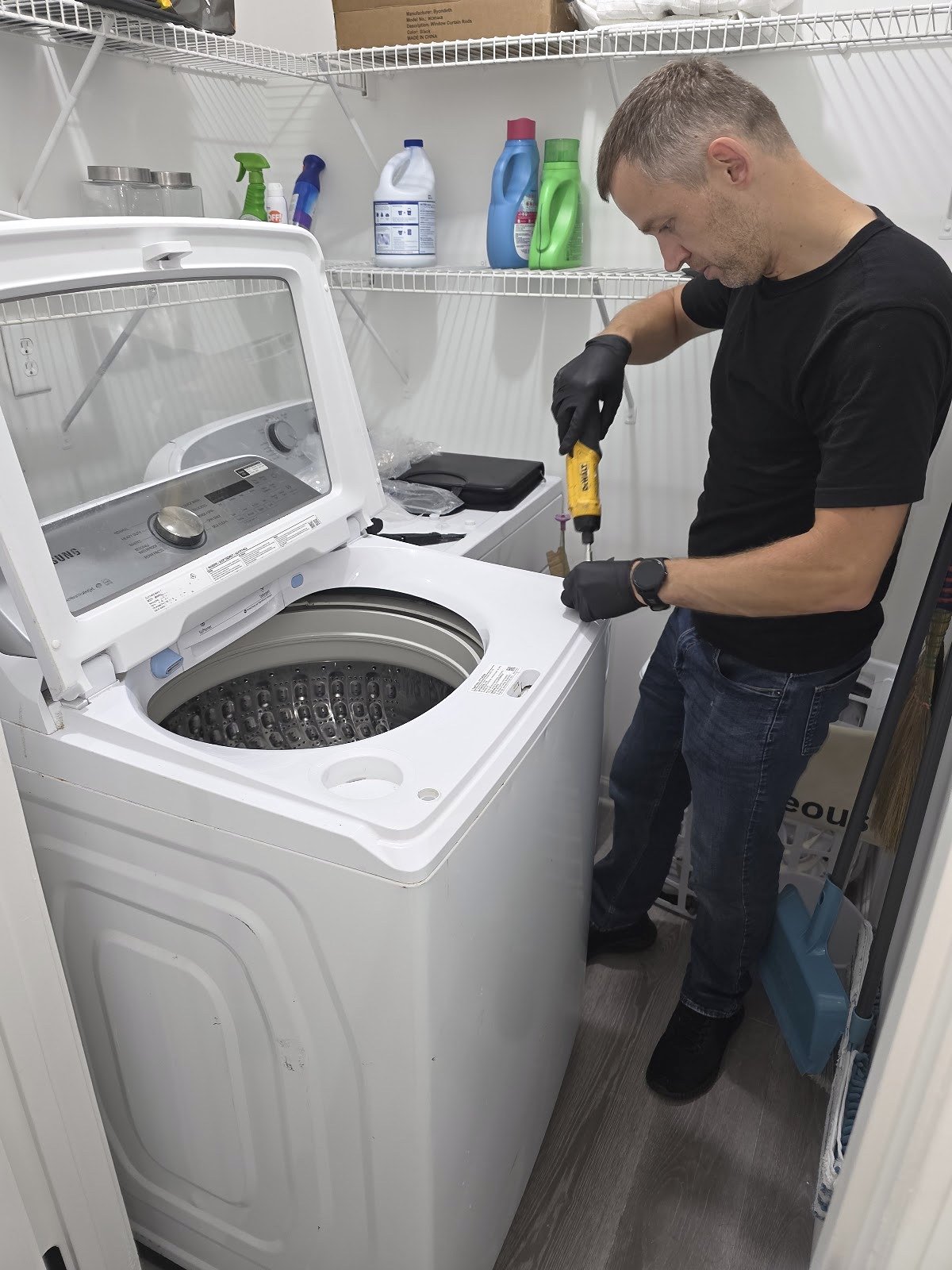 Technician working on a top-load washer with its lid open